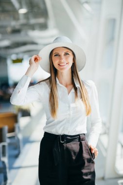 Havalimanı terminalinde kameraya poz veren neşeli, zarif bir yolcu.