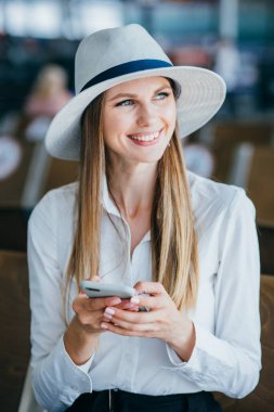 Güzel bayan havaalanında bankta oturuyor.