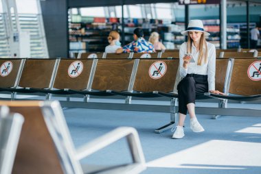 Genç kız hafta sonları seyahat etmek için uluslararası havaalanındaki uçuşu kontrol etmek için akıllı telefon kullanıyor..