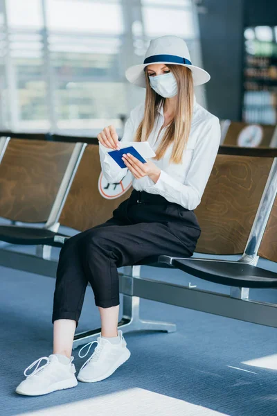 Pandemian matkat. Onnellinen nuori nainen suojaava lääketieteellinen naamio poseeraa lentokentän terminaalissa, rokotettu tuhatvuotinen Lähi-idän Lady Holding passit ja liput ja katsot kameraa, vapaata tilaa — kuvapankkivalokuva