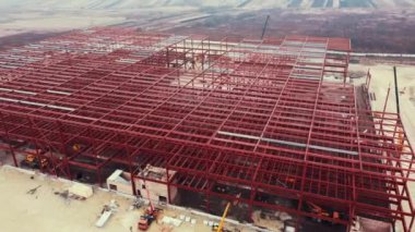 Metal yapıdan Depo İnşaatı. Işık göstergeli çelik çerçeveli sanayi binası. Yeni endüstriyel kompleksin şantiyesinde büyük metal bir leş.