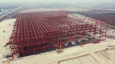 Metal yapıdan Depo İnşaatı. Işık göstergeli çelik çerçeveli sanayi binası. Modern hangar veya fabrika çerçevesi. Çelik yapı deposu olan bir inşaat alanı. Çatıdaki üst görünüm.