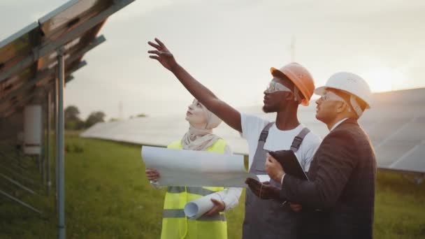 Multi ethnic people discussing work at solar station. African american technician talking with muslim woman and indian man during working session on solar station. — Stock Video