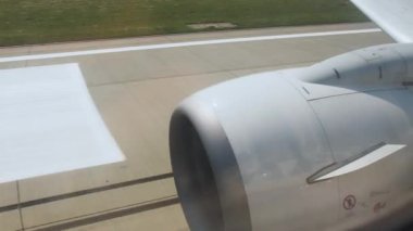 Havaalanında hareket eden bir uçağın penceresinden bak. Kalkışa hazırlanıyorum. Uçağın türbininin görüntüsü ve iniş pisti. Kalkış anı uçağı, uçak penceresinden görüş, gündüz.