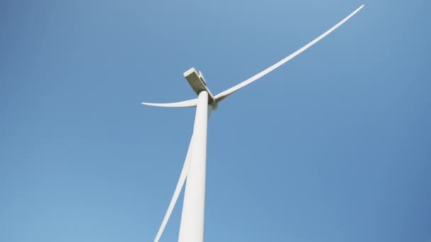 Close-up van enorme windpropeller werken voortdurend op eco-park boven de blauwe hemel. Concept van elektriciteitsproductie en schone energie. Close-up van windpropeller werkend op veld boven blauwe lucht — Stockvideo