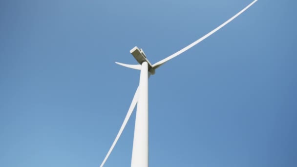 Rotující větrné turbíny. Zelená čistá energie budoucí koncept. Větrný mlýn se otáčí se sluncem na modré obloze. Skupina větrných mlýnů pro výrobu elektrické energie. Větrná vrtule pracující na poli nad modrou oblohou — Stock video