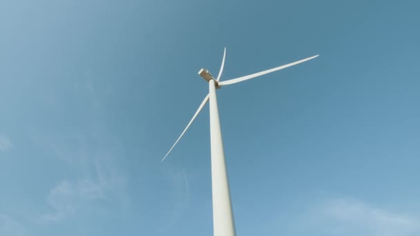 Detailní záběr obrovské větrné vrtule pracující neustále na ekologické farmě nad modrou oblohou. Koncepce výroby elektrické energie a čisté energie. Velké větrné turbíny s ostřím. Čistá obnovitelná energie — Stock video