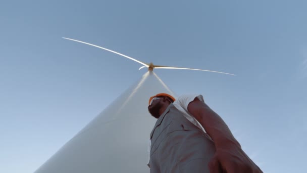 Portrétní inženýr poblíž větrných turbín, vyvinout ekologickou energii. Koncept znečištění životního prostředí, nové technologie alternativní energie. Inženýr v montérkách stojící mezi větrnými mlýny — Stock video