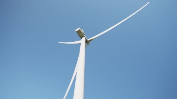 Detailní záběr obrovské větrné vrtule pracující neustále na ekologické farmě nad modrou oblohou. Koncepce výroby elektrické energie a čisté energie. Detailní záběr větrné vrtule pracující na poli nad modrou oblohou — Stock video