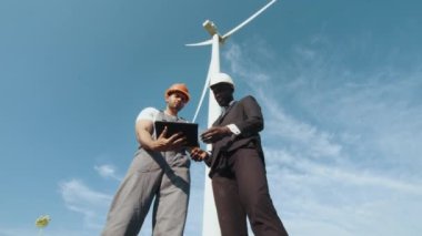 Afro-Amerikan şık takım elbiseli müfettişle görüşürken miğfer ve üniformalı Hintli mühendis tablet kullanıyordu. İki ortak yeşil enerjiyi tartışıyor. Yel değirmeni çiftliğinde birlikte çalışıyoruz.