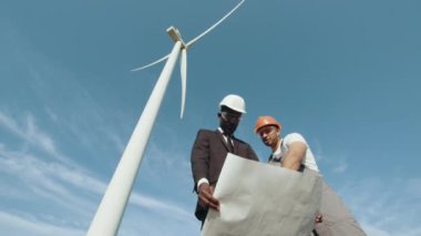 Elinde planları olan Afrika kökenli Amerikalı bir müfettiş, rüzgar türbinli çiftlikler arasında gebe kalan Hintli bir mühendisle sohbet ediyor. İki meslektaş açık hava projesini tartışıyor. Müfettiş-mühendis