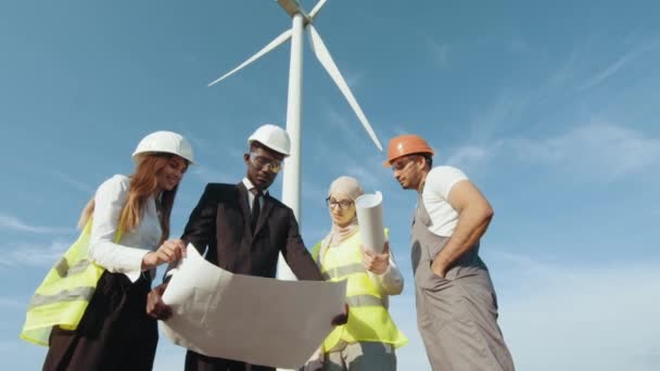 Les ingénieurs explorent les futurs projets d'installation d'éoliennes. Travail d'équipe, remue-méninges, énergies renouvelables. éoliennes énergie écologique industrie éolienne usine éolienne terrain travailleur renouvelable arrière-plan. — Video