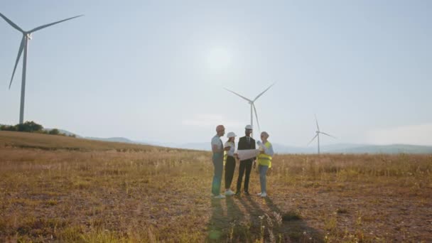 Rüzgar türbinleri tarlasında ya da çiftlikte temiz bir enerji kaynağı bulundurmak. Elektrik enerjisi için eko teknoloji. Endüstri. Mühendisler gelecekteki rüzgar türbini kurulum projelerini araştırıyorlar. — Stok video
