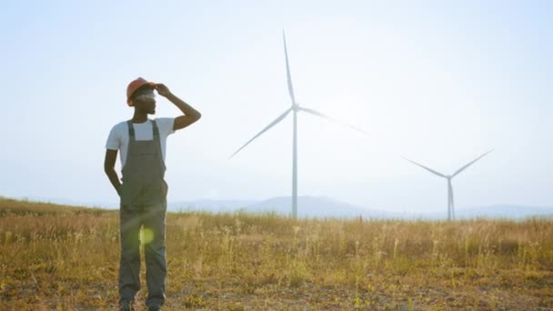 Engineer standing on field with windmills. Dreaming of a clean and sustainable future for generations to come, heartwarming uplifting picture of clean energy for the environment — Stock Video