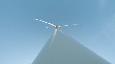 Dönen rüzgar türbinleri. Yeşil temiz enerji gelecek konsepti. Mavi gökyüzünde güneşle dönen yel değirmeni. Elektrik üretimi için bir grup yel değirmeni. Rüzgâr pervanesi mavi gökyüzünde çalışıyor
