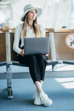 Uçuş için beklerken onu laptop çalışma genç şık iş kadını ile Uluslararası Havaalanı terminal, el bagajı