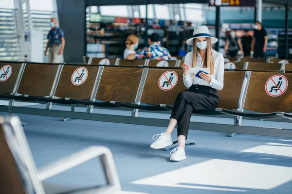 Frau mit Maske zur Vorbeugung gegen Virus mit Gepäck auf internationalem Flughafen. Schutz vor Coronavirus und Grippe — Stockfoto