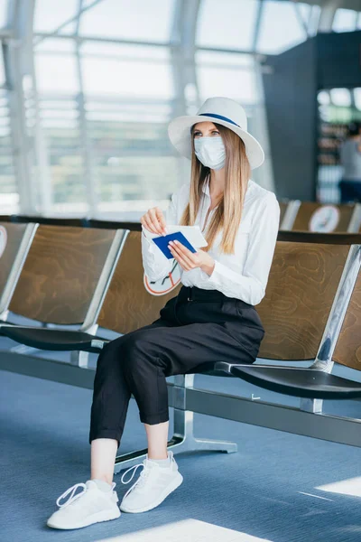 Vakker forretningskvinne på flyplassen, som bruker telefonen til å sende sms-er, står ved vinduet i kontorbygget og sjekker beskjeder. Jenta har billetter og pass. – stockfoto
