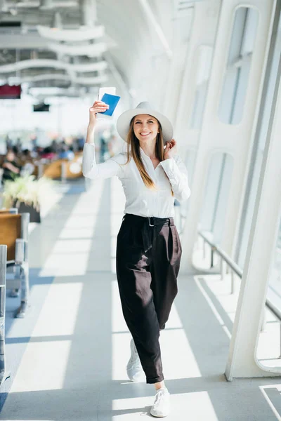 หญิงนักธุรกิจที่มีความสุขรอเที่ยวบินของเธอที่สนามบิน ผู้หญิงสาวที่สนามบิน ผู้หญิงกําลังรอเที่ยวบินในห้องโถงรออยู่ที่สนามบิน ผู้หญิงนักเดินทางที่มีความสุขกําลังรอเที่ยวบิน — ภาพถ่ายสต็อก