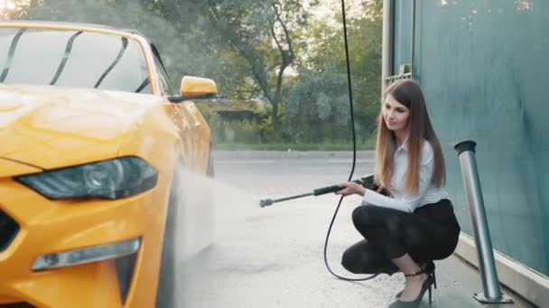 Tiro horizontal de mulher de negócios vestindo em uma camisa e calças, lavando sua roda de carro amarelo — Vídeo de Stock