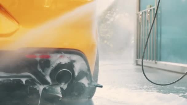 非洲自信的男性创业者西服，在户外自助洗浴服务中，用手用高压水软管冲洗他的黄色汽车。洗车概念。户外洗浴. — 图库视频影像