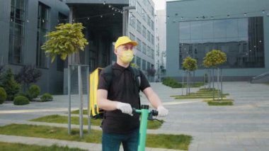 Covid 19 virüsünün ortaya çıkmasından dolayı maske takan bir teslimatçı scooter sürüyor ve yemek dağıtıyor. Bulanık geçmişi olan bir adama odaklan. Kurye, teslimat servisi. Modern ofis geçmişi