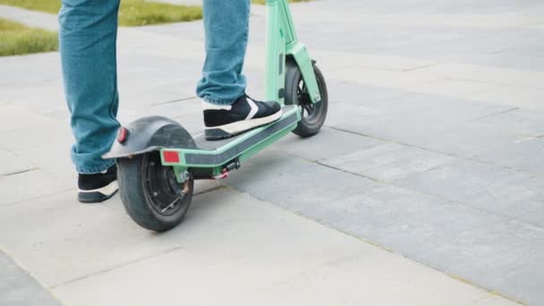 Gros plan des jambes masculines en scooter électrique à l'extérieur de la ville urbaine. Un gars qui utilise une mobilité écologique dans la ville. Courrier livraison de nourriture tour sur scooter électrique livrer client de commande en ligne. — Video