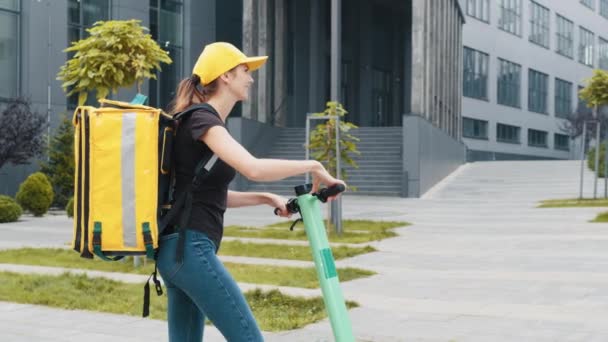 Man kurir matleverans med gul termisk ryggsäck rider på gatan på en elektrisk skoter leverans online beställning kund. Utmärkt leverans. Leverans av ekologiska varutransporter — Stockvideo