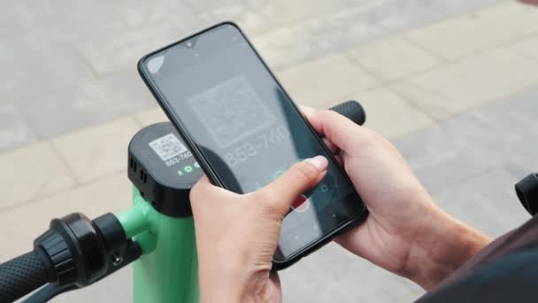 Mulher digitalizar código QR por telefone inteligente para desbloquear e alugar scooter elétrico empurrar na rua. Eco transporte amigável na cidade. Fecha. Transporte ecológico. Tecnologias modernas. — Vídeo de Stock