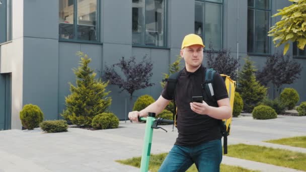 Endereço de navegação do homem de entrega no aplicativo de GPS de mapa de telefone móvel para ordem de fast food montando scooter elétrico - Concentre-se no rosto do homem correio — Vídeo de Stock