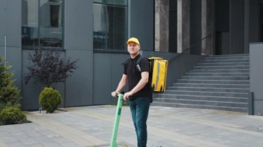 Kuryeler mal teslimatı için emirleri yerine getirirler. Yemek teslimatı. Kurye Adam Restoran Yemekleri Kutuda, E-Motosiklette Poz Veriyor.