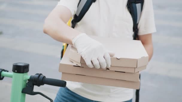 Pizza-Lieferung. Nahaufnahme Unbekannter Liefermann mit Schutzmaske und Handschuhen mit Pizzaschachtel in Nahaufnahme. Zusteller streckt einen Stapel Pizzakartons aus. Pizzaboten-Angebot — Stockvideo