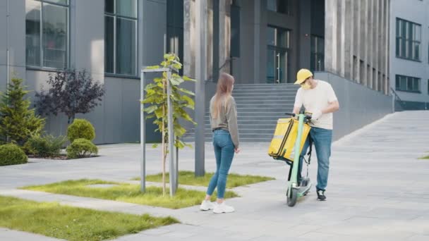 Mädchen holt Lieferbox von Lieferfahrer mit Roller vor Haus ab, um soziale Distanzierung für Infektionsrisiko zu gewährleisten. Frau nimmt die Lieferung einer Tüte vom Zusteller an. Kurierdienst. — Stockvideo