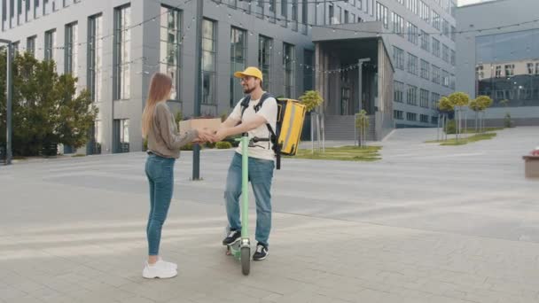 Mensajero entregando un paquete. Una joven sonriente abre una caja de cartón y saca los zapatos. Entrega en una tienda de ropa en línea. Entrega de zapatos. Compras online — Vídeos de Stock