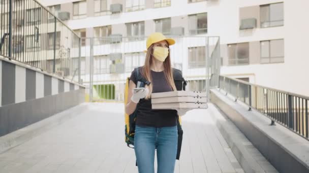 Retrato de una mensajera entregando un pedido de comida por la ciudad. Mujer entrega cajas usando un teléfono inteligente en la calle en la ciudad. El mensajero habla con el cliente por teléfono. Entrega de pizza — Vídeo de stock