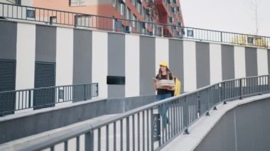 Çevrimiçi market alışverişi, genç evli kadın kurye olarak çalışıyor, internet üzerinden alışveriş yapıyor. Paketli pizzası olan güzel bir kadın kurye. Termal sırt çantalı kadın akıllı telefona bakıyor.