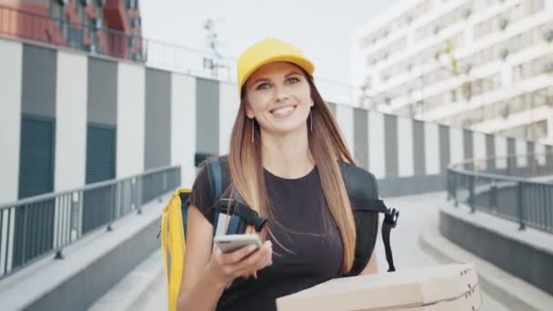 Delivery woman with thermal backpack holding mobile phone. Happy female courier working in food, pizza delivery service. Delivery concept food. Online food shopping. Food delivery from restaurant — Stock Video