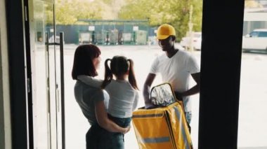 Küçük bir kızı olan güzel genç bir kadın evinin kapısını açar ve ona online bir mağazadan gelen karton bir posta kutusunu veren Afro-Amerikan bir kuryeyle tanışır. Kutu teslimatı