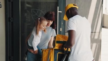 Küçük bir kızı olan genç bir kadın Afro-Amerikan bir kuryeyle tanışır. Afro-Amerikan kurye çevrimiçi bir mağazadan bir paket veya hediye getiriyor, aile ekspres teslimatı, e-ticaret hizmeti konsepti