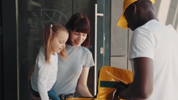아프리카 계 미국인 택배 회사는 온라인가게, 가족의 급식소, 전자 상거래 서비스 개념에서 소포나 선물을 가져왔다. 어린 딸을 둔 한 젊은 여자가아 프리카 계 미국인 택배를 만나다. — 비디오