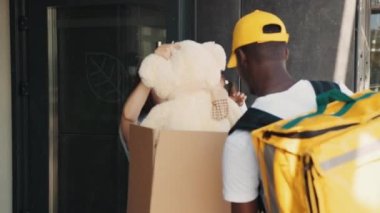 Kurye, annesinin kapısında olduğu küçük bir kıza bir paket getirdi. Paketi açarken, mutlu bir çocuk pofuduk bir oyuncak ayıyı kutusundan çıkarır, süprizle sevinir, aile teslimatı