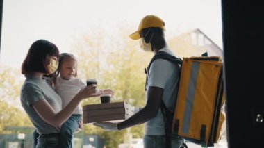 Evinin kapısında bir çocukla gülümseyen güzel bir genç kadın ve ona karton kutu dolusu lezzetli buharda pişmiş pizza veren bir pizzacıyla tanışır. Yemek dağıtan adam.