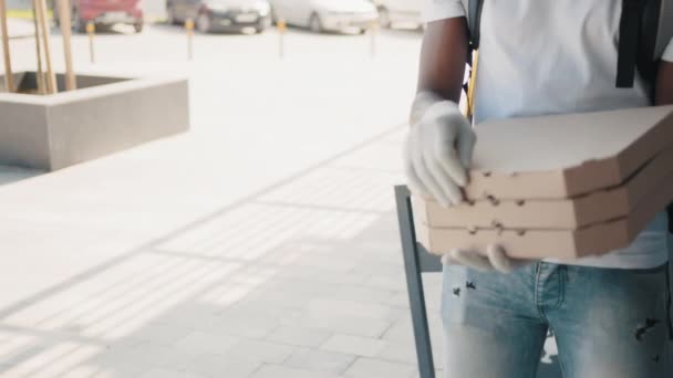 Essen zu Hause während des Coronavirus. Schöne junge lächelnde Frau mit Kind vor der Tür ihres Hauses und trifft einen Pizzaboten, der ihr Kartons voller köstlicher gedämpfter Pizza reicht. — Stockvideo
