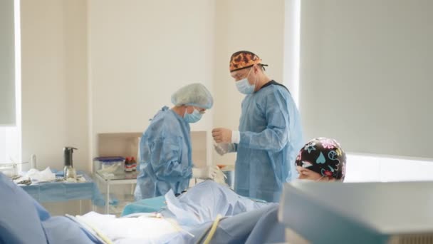 Chirurgie, medicína a pojetí lidí. Operační asistent pomáhá chirurgovi tím, že si obléká sterilní oděv. Příprava na operaci, záchrana života, intenzivní péče, mechanické větrání. — Stock video