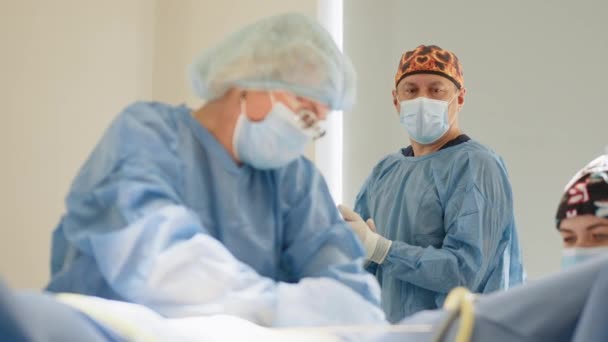Χειρουργοί ομάδα εκτελεί λειτουργία στο νοσοκομείο χειρουργικό θέατρο, αρσενικό χειρουργό χειρουργική ασθενή, φορώντας χειρουργική τήβεννο, χειρουργείο,, εργάζονται με χειρουργικά εργαλεία λαπαροσκόπησης. Γυναικολογία. — Αρχείο Βίντεο
