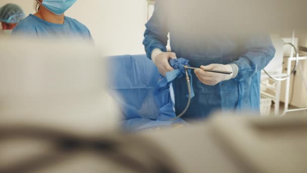 Laparoscopic instrument. Close up of male hands in white sterile gloves holding laparoscopic instrument. The surgeons doing laparoscopic surgery in the operating room. Minimally invasive surgery. — Stock Video