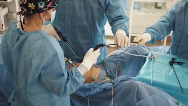 Operasi laparoskopi proses nyata. Tim ahli bedah melakukan persiapan operasi di ruang operasi rumah sakit, pasien operasi pria, mengenakan gaun bedah, ruang operasi. — Stok Video