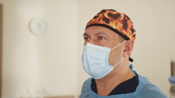 전문 의사의 초상화. 백인 외과의사 남성 건강 관리 전문의 외과 캡 과 마스크를 착용 한 채 병원 수술실에서 일하고 있습니다. 병원에서 수술받고 있는 의사 — 비디오