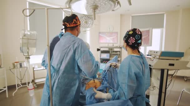Läkarteam utför kirurgisk operation i ljusa moderna operationssalen. Läkare som opererar en patient som ligger på operationsbordet. Grupp kirurger i operationssalen — Stockvideo