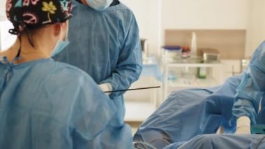 Karın ameliyatı sırasında laparoskopik aletler çalışıyor. Yakın plan çekim. Hastane ameliyathanesinde laparoskopik müdahalede bulunan doktorlar işbirliği yapıyor. Modern olarak laparoskopi